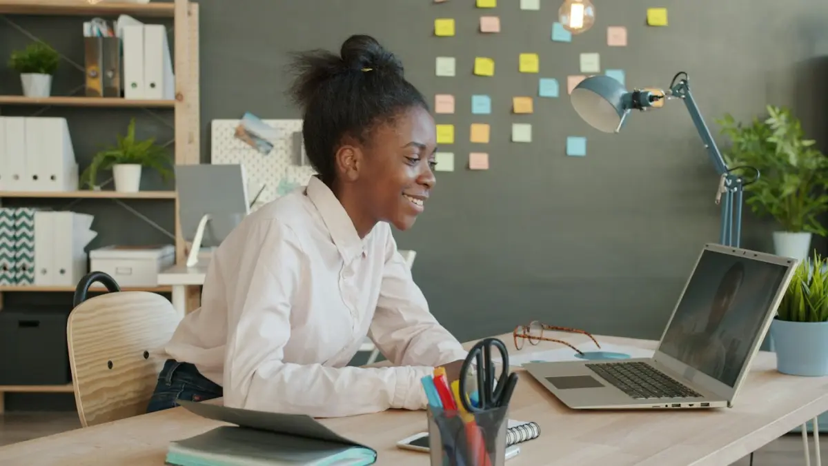 A woman smiling on a video call at her desk